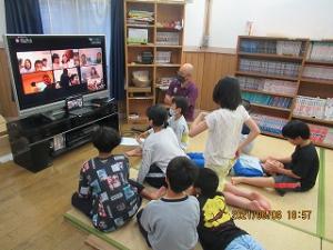 モニターに映る家族に笑顔する留学児童の写真