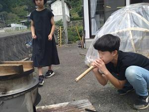 火吹き竹で火力を上げる留学児童の写真