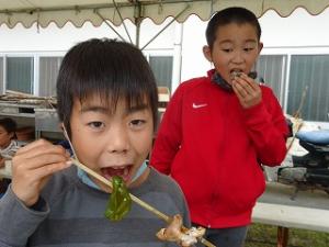 釣ったマスを美味しく食べる留学児童の写真