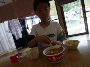 お揚げをだしに浸す留学児童の写真