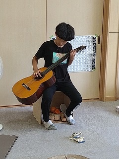 ギターを弾く感じを出す留学児童の写真