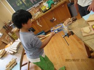 鋸で木材を切る留学児童の写真