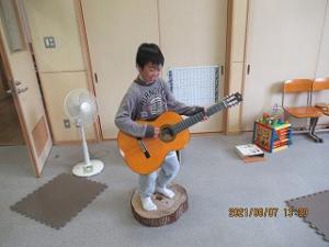 アーティスト気分でギターを弾く留学児童の写真