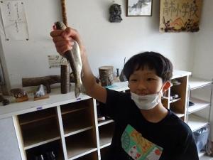釣り上げたマスを誇らしげに見せる留学児童の写真