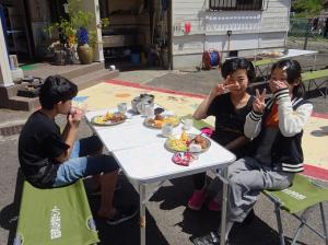 ピースサインをしながら楽しくお昼ご飯を食べる留学児童の写真