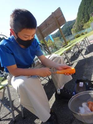 ピーラーでニンジンの皮をむく留学児童の写真