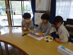 机の前で完成をイメージする留学児童の写真
