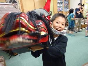大きな獅子頭に興奮する留学児童の写真
