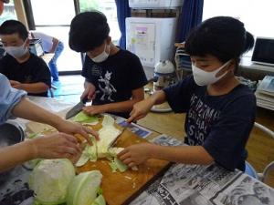 キャベツを刻む留学児童の写真