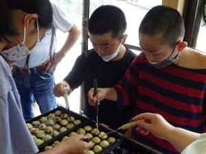たこ焼きに集中する留学児童の写真