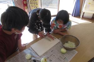 チームで協力して調理する留学児童の写真