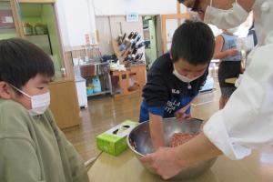 ひき肉をこねる留学児童の写真