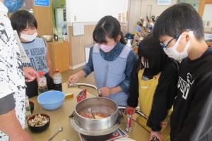 釜飯の味付けをする留学児童の写真