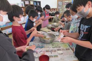 丁寧に餡を包む留学児童の写真