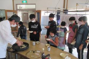 餃子が焼けるたびに行列を作る留学児童の写真