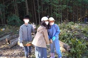 思い原木を協力して運ぶ留学女子の写真