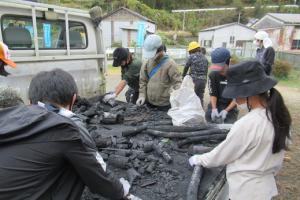 トラックの荷台で炭を切る留学児童の写真