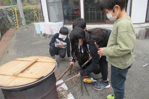 大鍋でお湯を沸かす留学児童の写真