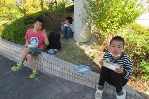 日陰を探して昼食をとる留学児童の写真