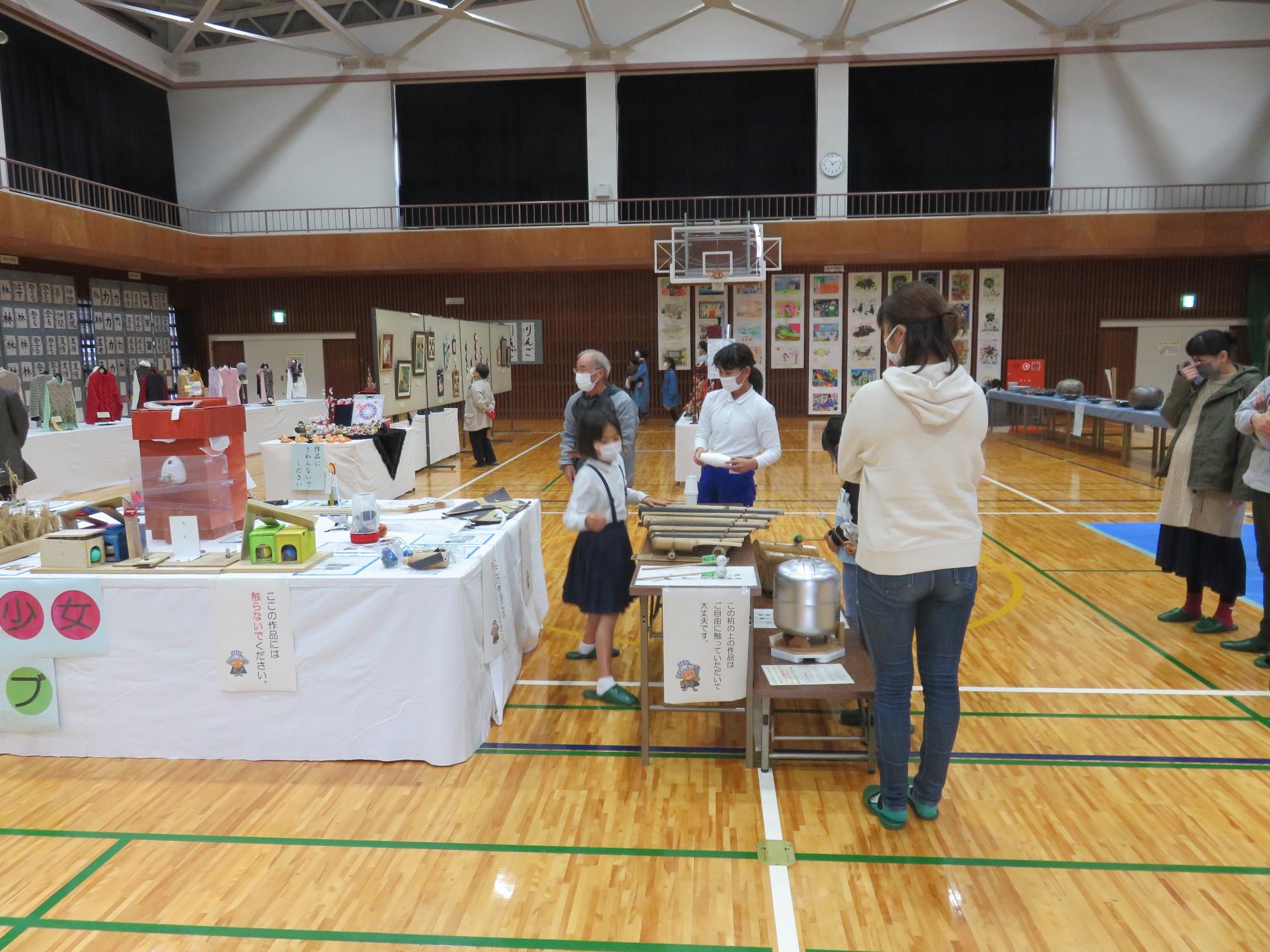 体育館に作品展示したものを様々な年代の人が興味深げに見ている様子