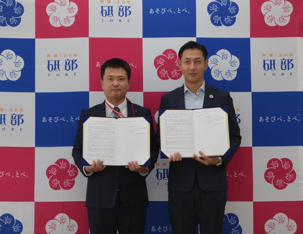 砥部町長と原町郵便局長がそれぞれ協定書を持って並んでいる写真