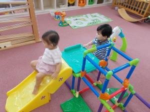 乳幼児用の滑り台を使って遊ぶ、2人の乳幼児の様子を写した写真